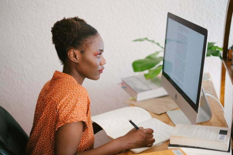 a person sitting at a desk writing on a book