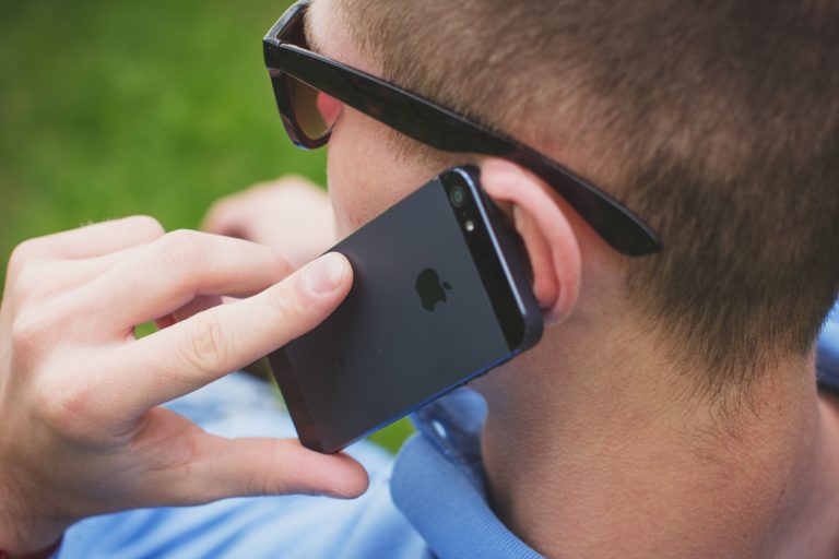 a man wearing glasses and holding a cell phone