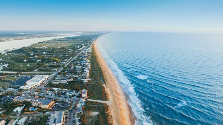 a beach with a long road and buildings on the side